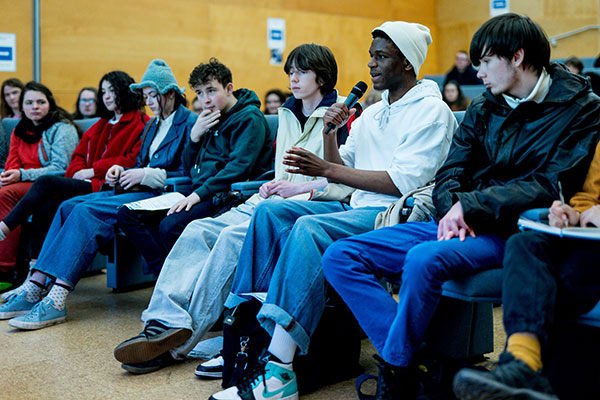 Young people asking questions in lecture theatre